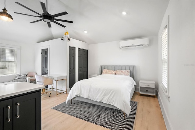 bedroom with baseboards, vaulted ceiling, light wood-type flooring, a closet, and a wall mounted AC