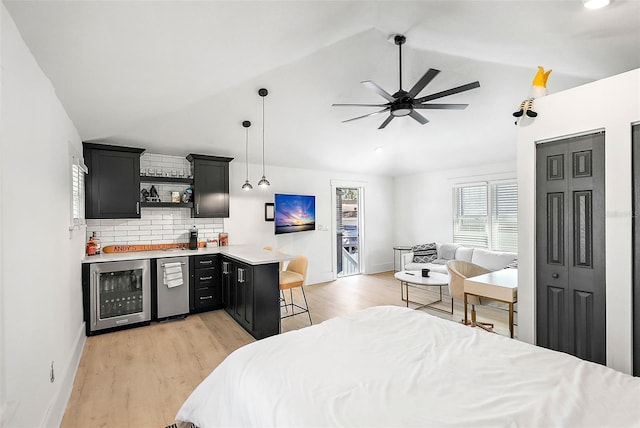 bedroom with beverage cooler, lofted ceiling, light wood-style flooring, and baseboards