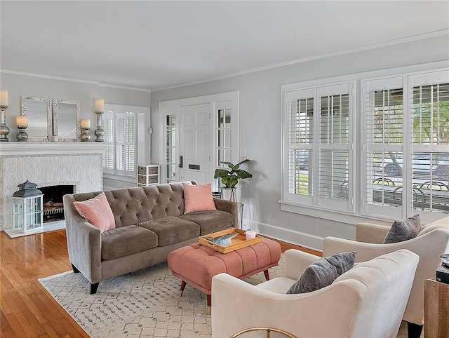 living room featuring baseboards, a fireplace, light wood-style flooring, and crown molding