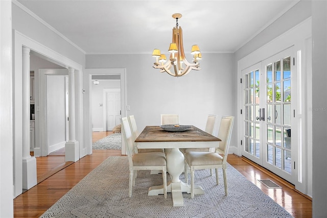 dining space featuring a chandelier, wood finished floors, visible vents, and crown molding