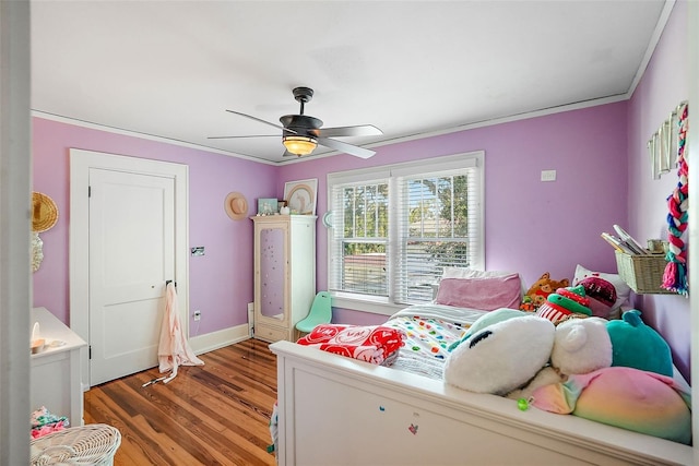 bedroom featuring a ceiling fan, crown molding, baseboards, and wood finished floors