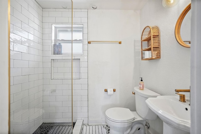 full bath featuring a tile shower, a sink, and toilet