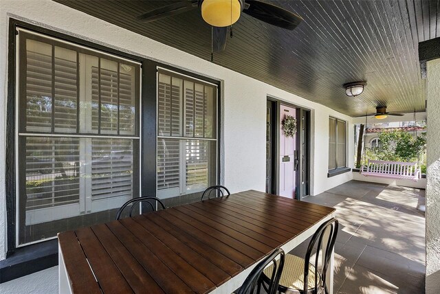 wooden terrace with ceiling fan, a porch, and outdoor dining area