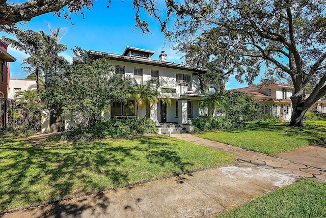 traditional style home with a balcony, a front lawn, and stucco siding