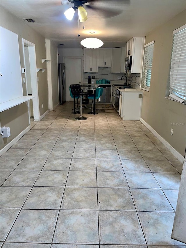 kitchen with decorative backsplash, white cabinets, ceiling fan, appliances with stainless steel finishes, and sink