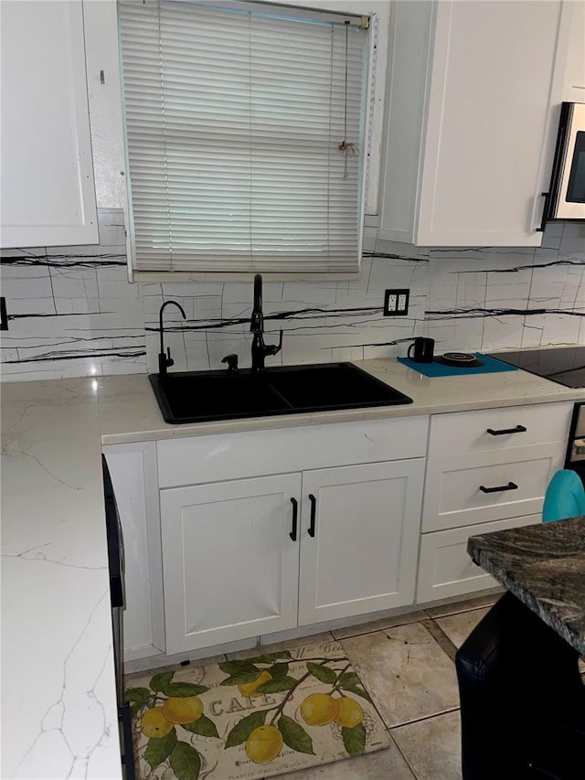 kitchen with white cabinetry, sink, and light stone counters