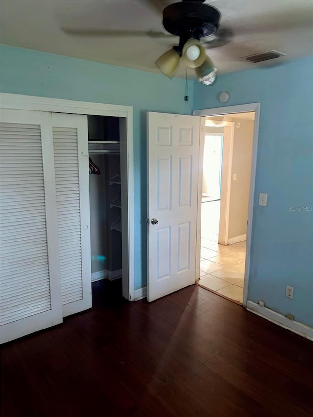 unfurnished bedroom featuring a closet, dark hardwood / wood-style floors, and ceiling fan