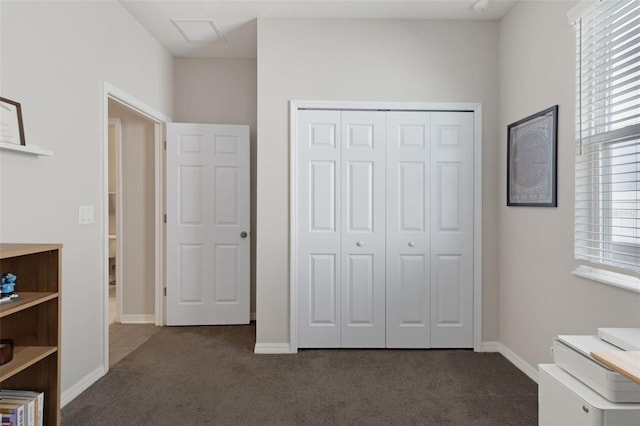 unfurnished bedroom with a closet and dark colored carpet