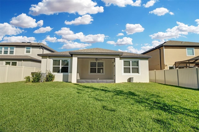 rear view of property featuring a lawn and ceiling fan