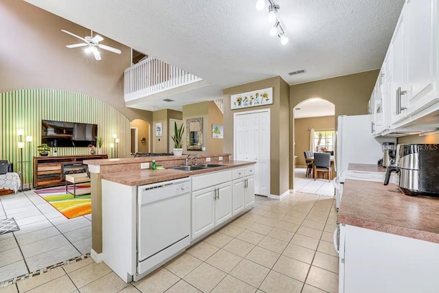 kitchen with light tile patterned floors, white cabinetry, a textured ceiling, white dishwasher, and sink