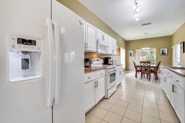 kitchen with white appliances, light tile patterned flooring, pendant lighting, and white cabinets