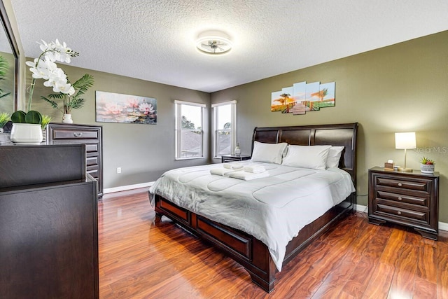 bedroom featuring a textured ceiling and dark hardwood / wood-style flooring