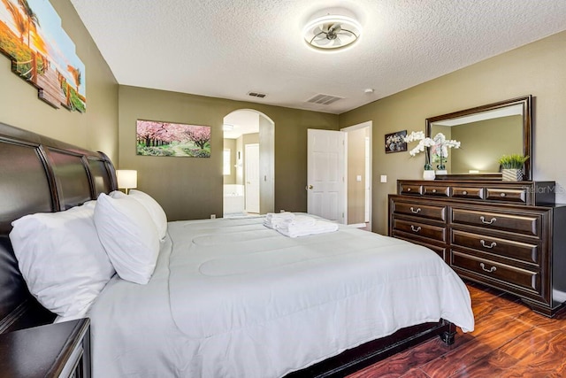 bedroom with dark wood-type flooring, ensuite bathroom, and a textured ceiling