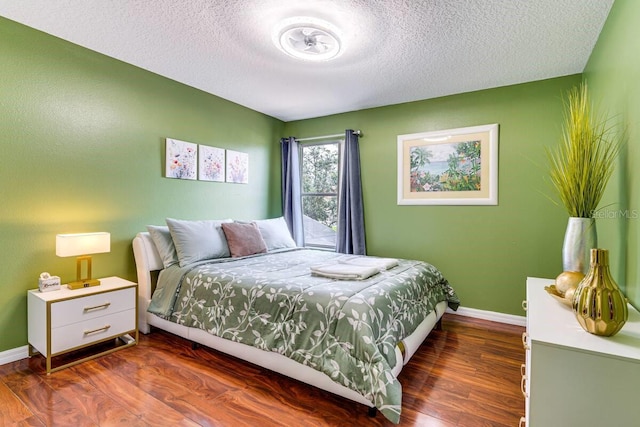 bedroom with a textured ceiling and dark hardwood / wood-style floors