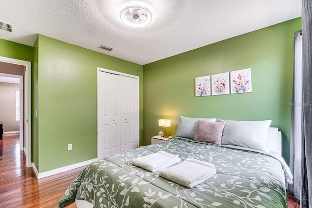 bedroom with a closet, a textured ceiling, and hardwood / wood-style floors