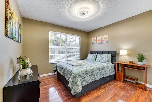 bedroom with dark wood-type flooring and a textured ceiling