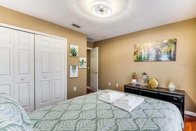 bedroom featuring a closet, dark wood-type flooring, and a textured ceiling