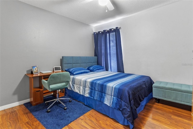 bedroom with a textured ceiling, hardwood / wood-style flooring, and ceiling fan