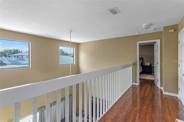 hall featuring a textured ceiling and dark hardwood / wood-style floors