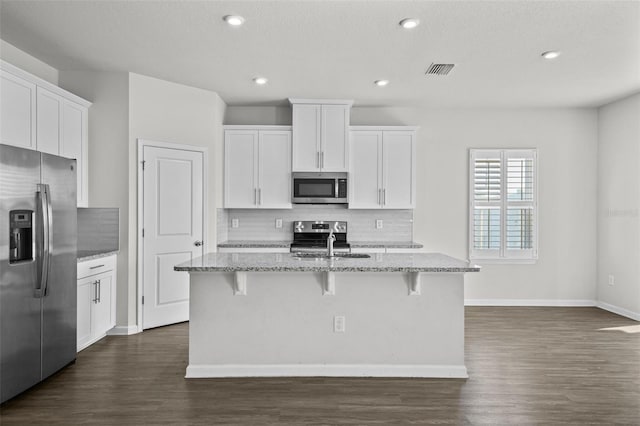 kitchen featuring appliances with stainless steel finishes, white cabinets, and a kitchen island with sink