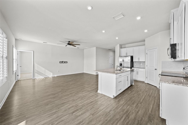 kitchen with white cabinets, a center island with sink, appliances with stainless steel finishes, and decorative backsplash