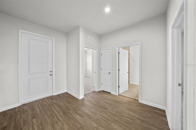 unfurnished bedroom featuring ensuite bathroom and wood-type flooring