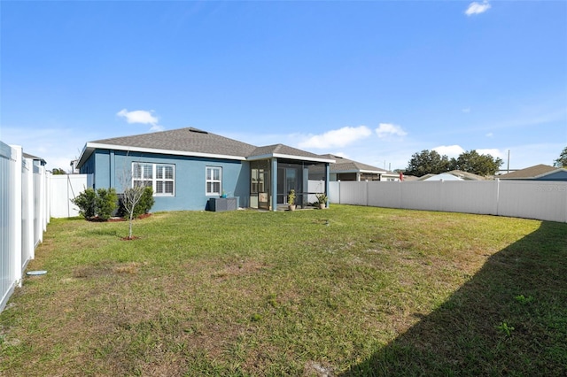 rear view of property with a yard, central AC unit, and a sunroom