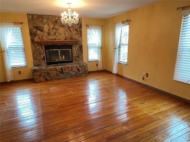 unfurnished living room with an inviting chandelier, hardwood / wood-style floors, and a fireplace