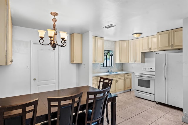 kitchen featuring decorative light fixtures, light tile patterned floors, an inviting chandelier, sink, and white appliances