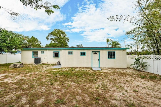 rear view of house with central AC unit and a yard