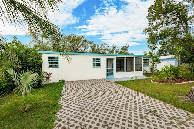 back of property with a sunroom and a yard