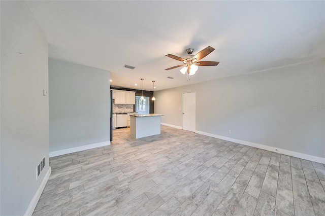 unfurnished living room featuring visible vents, baseboards, ceiling fan, and light wood-type flooring