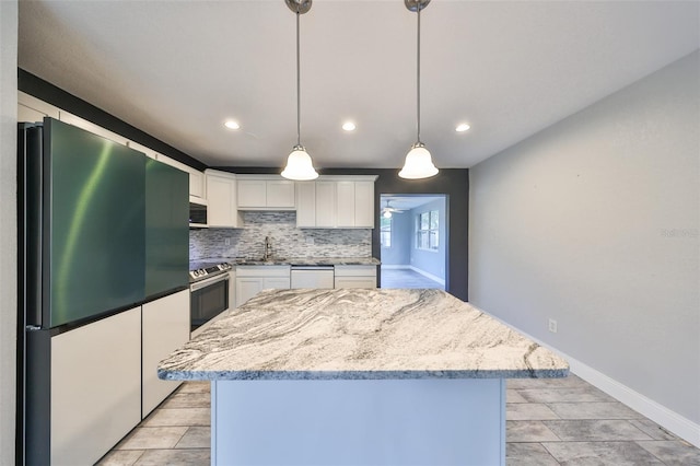 kitchen featuring appliances with stainless steel finishes, sink, a center island, white cabinetry, and pendant lighting