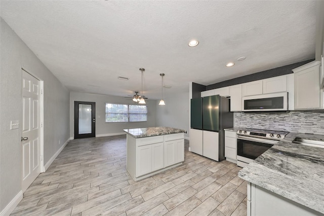 kitchen with light hardwood / wood-style flooring, white cabinets, hanging light fixtures, and stainless steel appliances