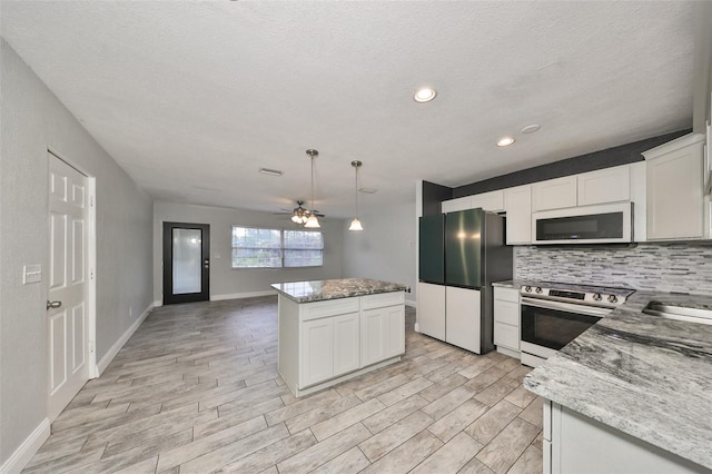 kitchen with decorative backsplash, stainless steel electric range, freestanding refrigerator, white microwave, and light wood-style flooring