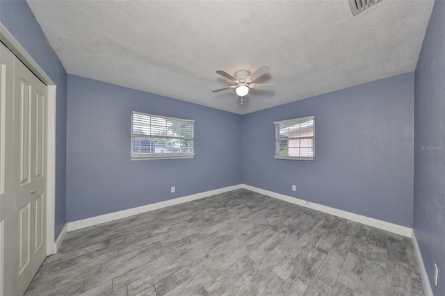 unfurnished bedroom with a closet, ceiling fan, wood-type flooring, and a textured ceiling