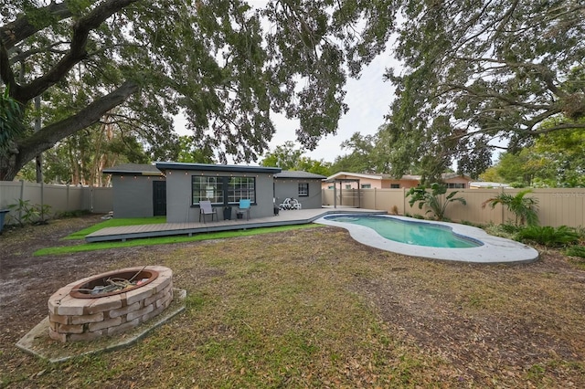 view of pool with a deck, a lawn, and a fire pit