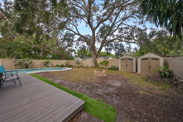 view of yard featuring a storage unit, a fire pit, and a swimming pool side deck