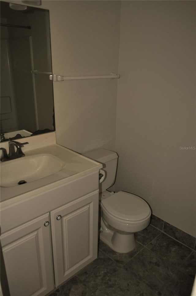 bathroom with toilet, vanity, and tile patterned floors