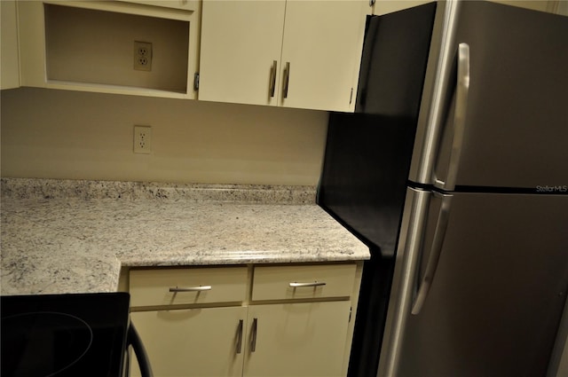 kitchen with stainless steel fridge, stove, and light stone counters