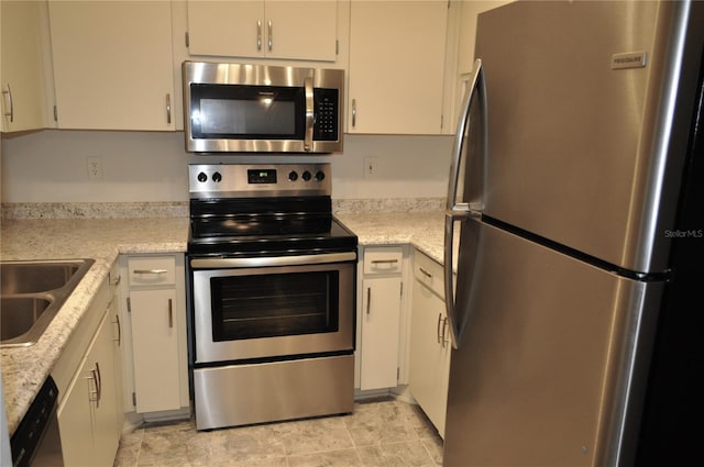 kitchen featuring white cabinetry, stainless steel appliances, sink, and light stone counters