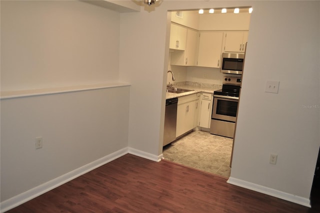 kitchen with white cabinets, light hardwood / wood-style floors, sink, and appliances with stainless steel finishes