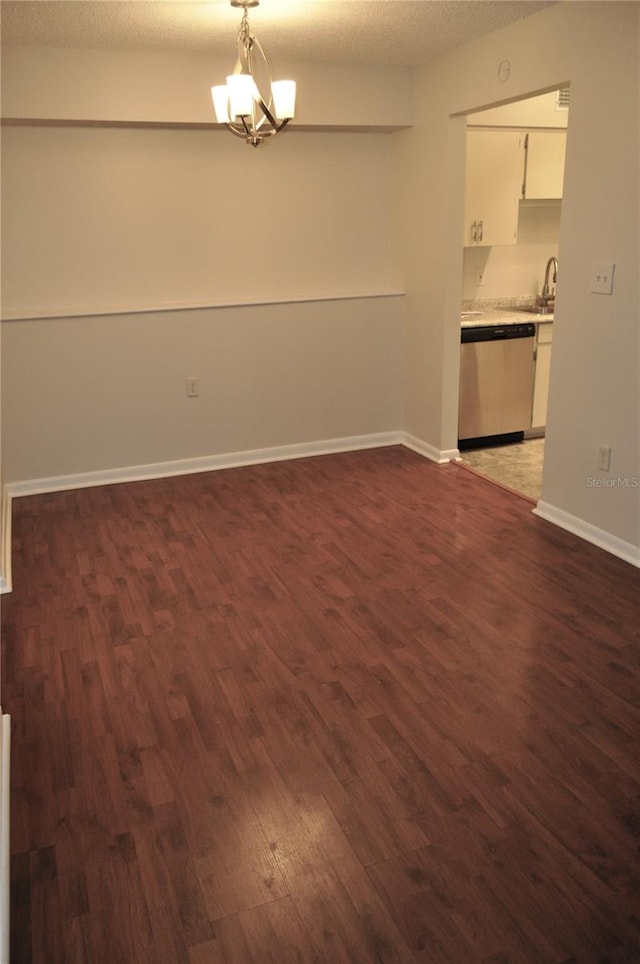 unfurnished room with dark wood-type flooring, sink, a chandelier, and a textured ceiling