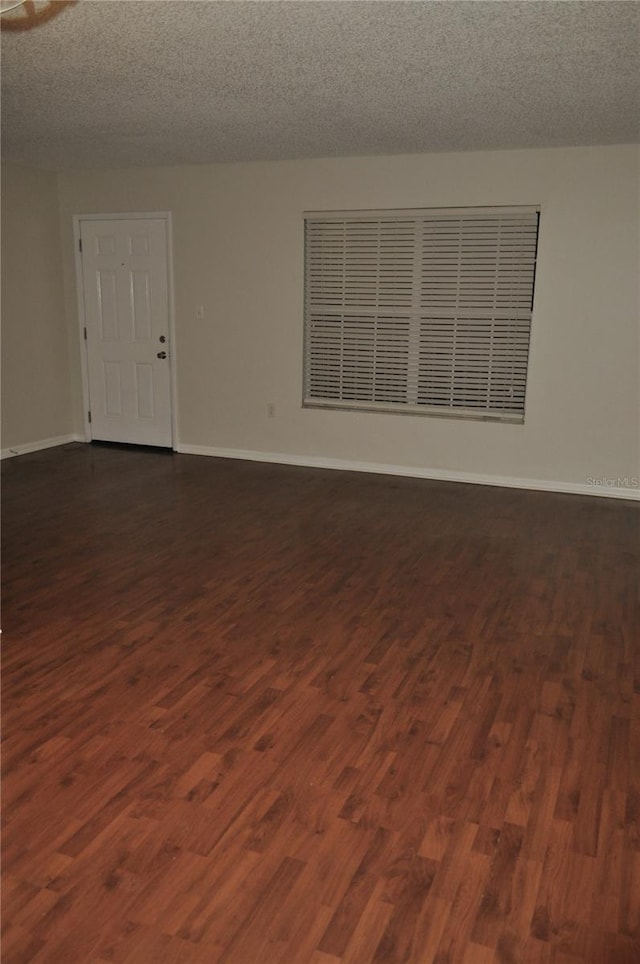 spare room featuring dark wood-type flooring and a textured ceiling