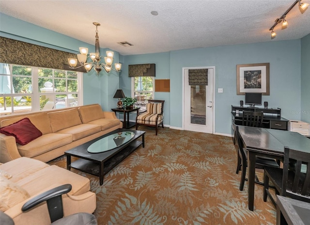 carpeted living room with a textured ceiling, a healthy amount of sunlight, and a chandelier