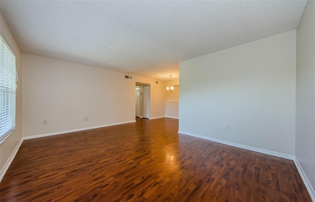 2690 Coral Landings Blvd Unit 722, Palm Harbor, FL 34684 - spare room featuring dark wood-style flooring, a chandelier, a textured ceiling, and baseboards