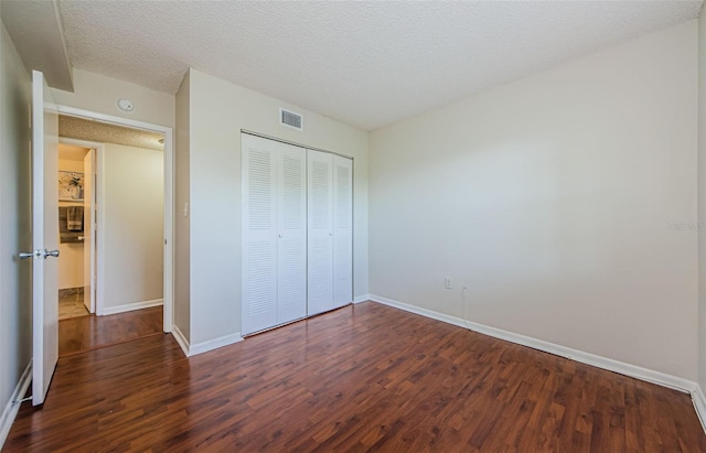 2690 Coral Landings Blvd Unit 722, Palm Harbor, FL 34684 - unfurnished bedroom with dark wood-style flooring, baseboards, a closet, and a textured ceiling