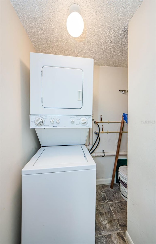 2690 Coral Landings Blvd Unit 722, Palm Harbor, FL 34684 - washroom featuring stacked washer and clothes dryer, a textured ceiling, and baseboards