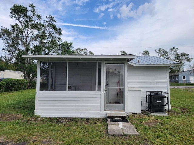 rear view of property featuring a sunroom, central AC, and a lawn