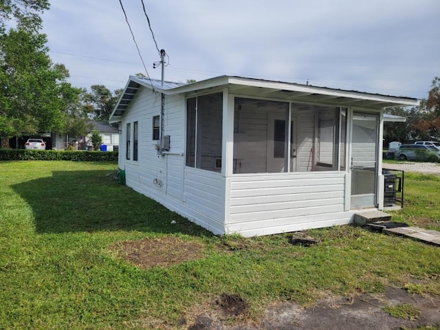 view of home's exterior featuring a sunroom and a lawn